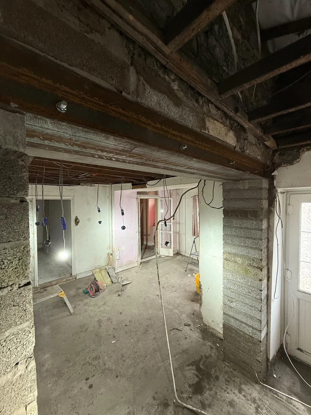 Two structural steel beams installed across open plan ground floor during a load bearing wall removal, supported on blockwork piers